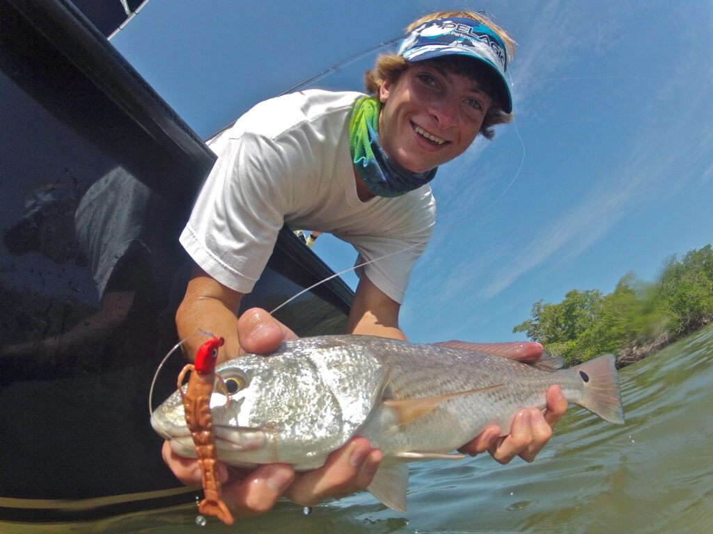 Angler holding a redfish with a Berkley Gulp Shrimp in its mouth.