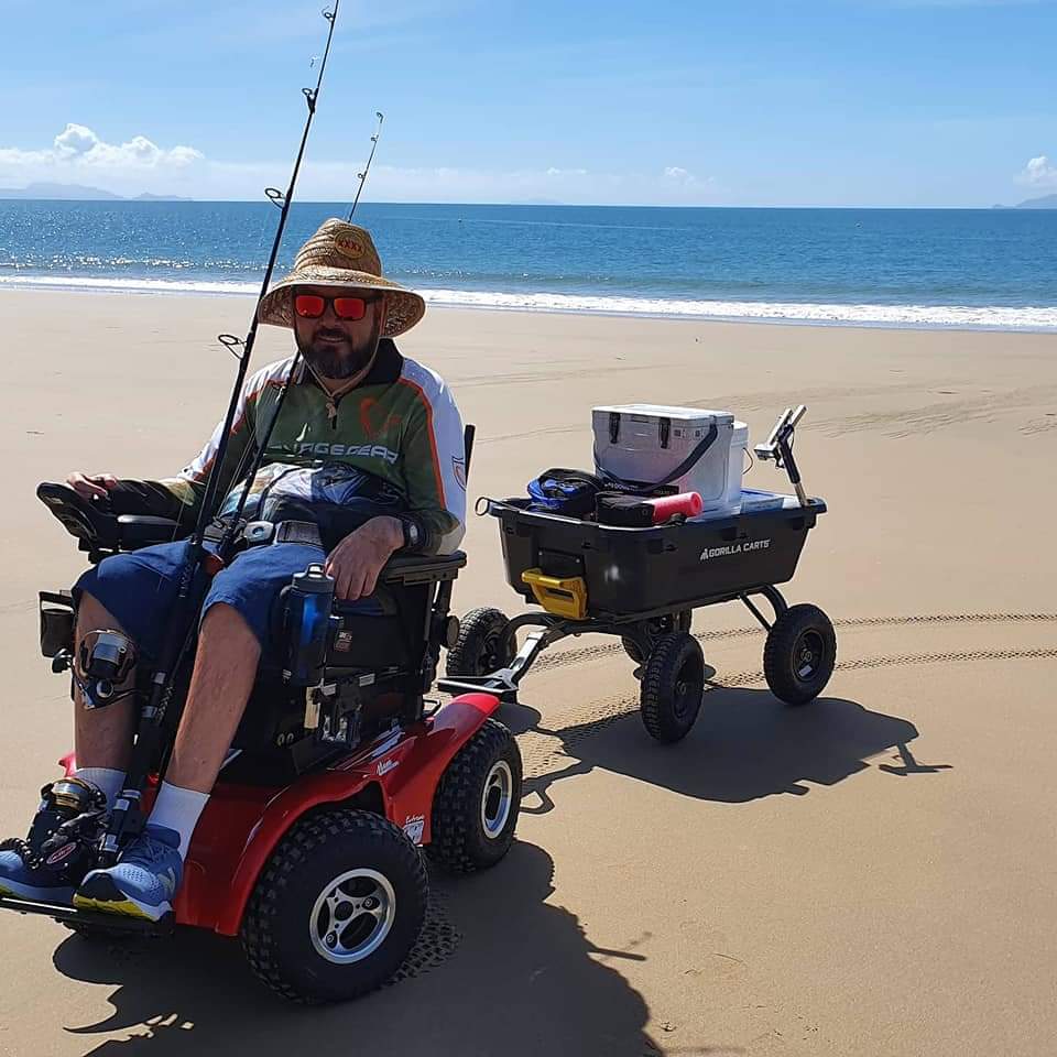 Man in motorized wheel chair pulling a beach cart - 5 Best Beach Carts