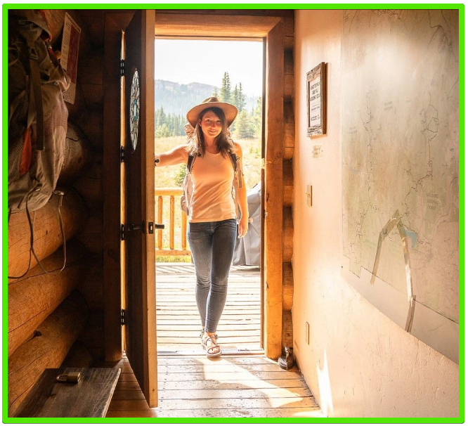 Lady coming in the cabin door wearing her Ibex Outdoor Clothing merino wool shirt and pants.