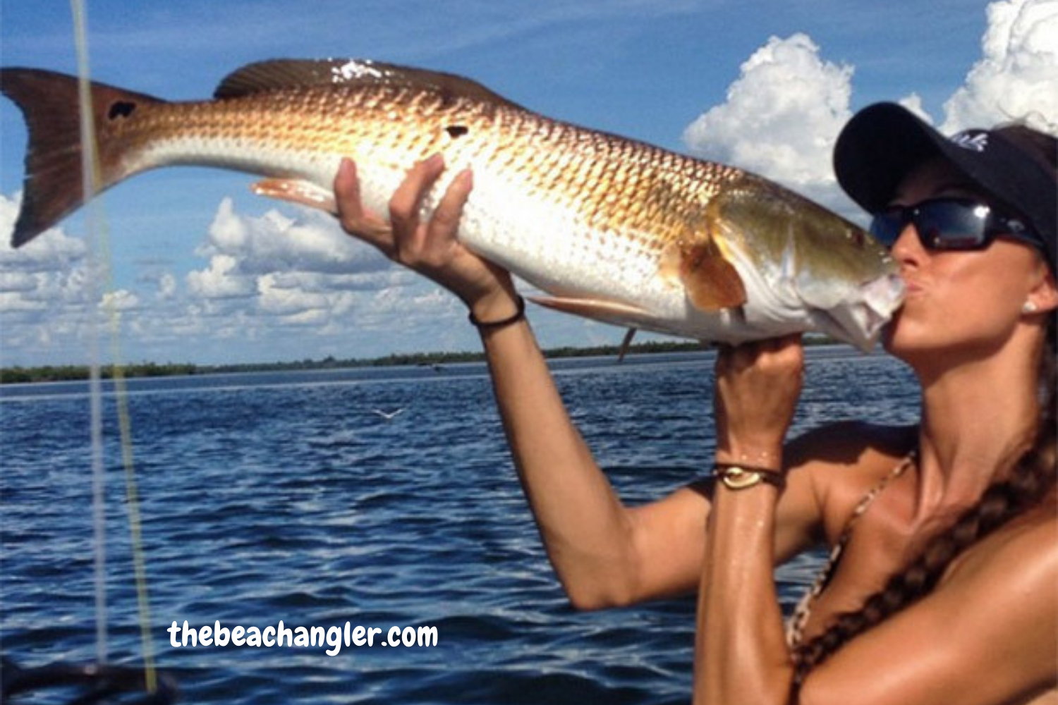 Lady giving a big kiss to a nice redfish caught from the surf