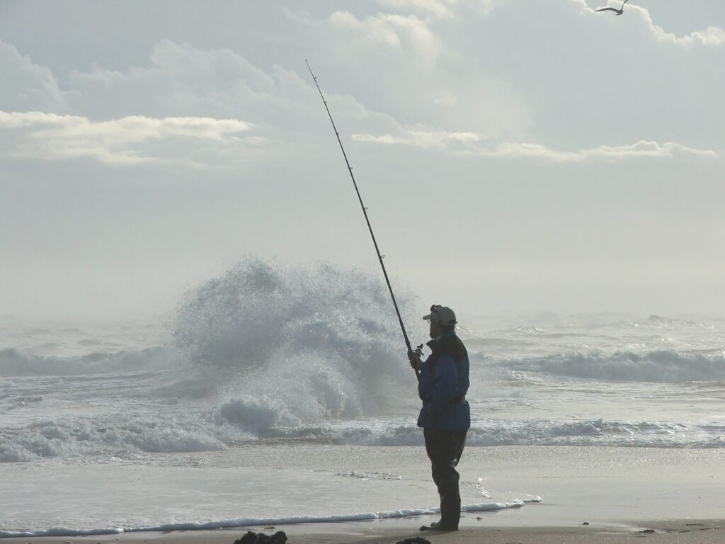 cold weather surf fishing - fisherman layered up to fish in the cold and rough surf