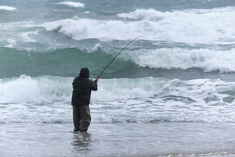 Fisherman hooked up with a nice fish in some very rough water conditions