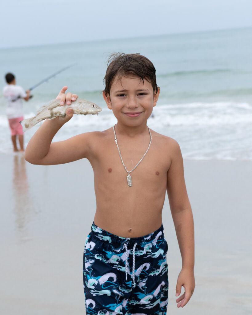 9 Essential Tips for Surf Fishing with Kids - Young boy with a nice whiting caught from the surf.