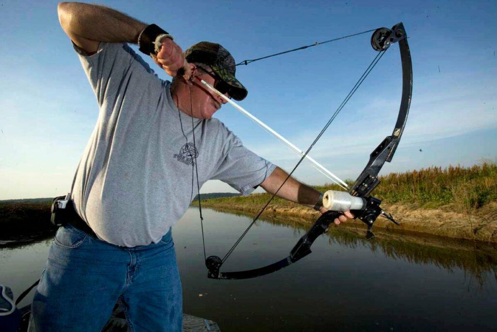 bowfishing how to for beginners - Bowfisherman setting up to take a shot from a boat