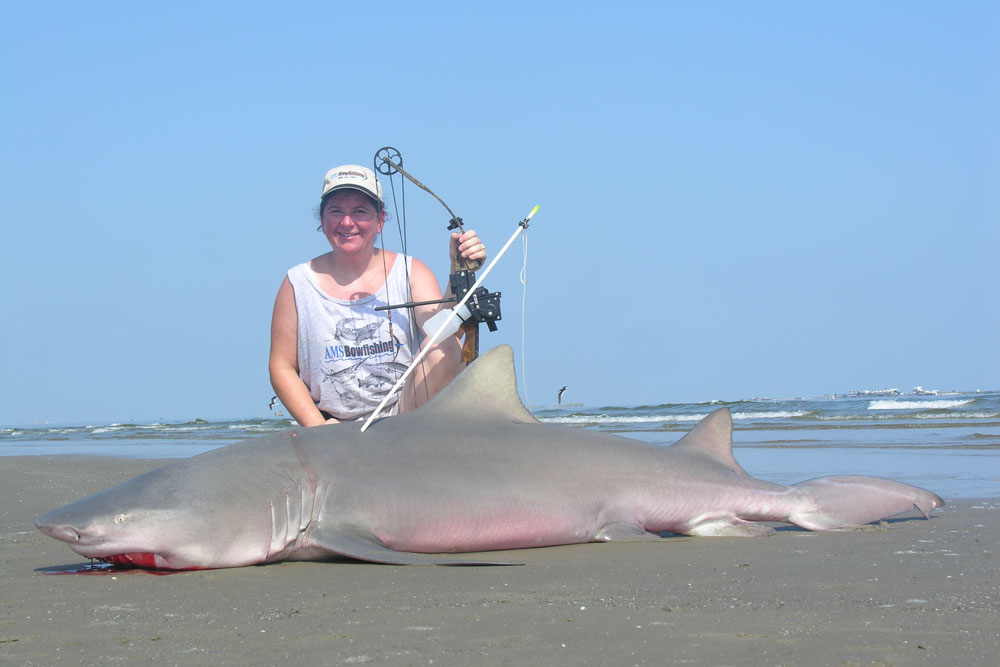 bowfishing how to for beginners - lady with a large shark taken while bowfishing the surf.