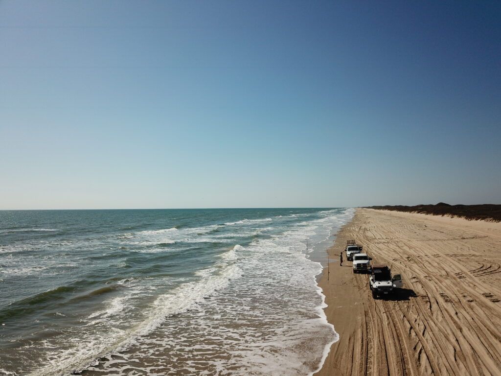 fishing on padre island national seashore - trucks lined along the waters edge with rods out waiting on the fish to bite.