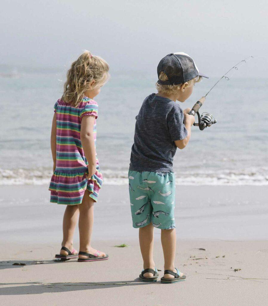 Little boy and little girl fishing from the beach