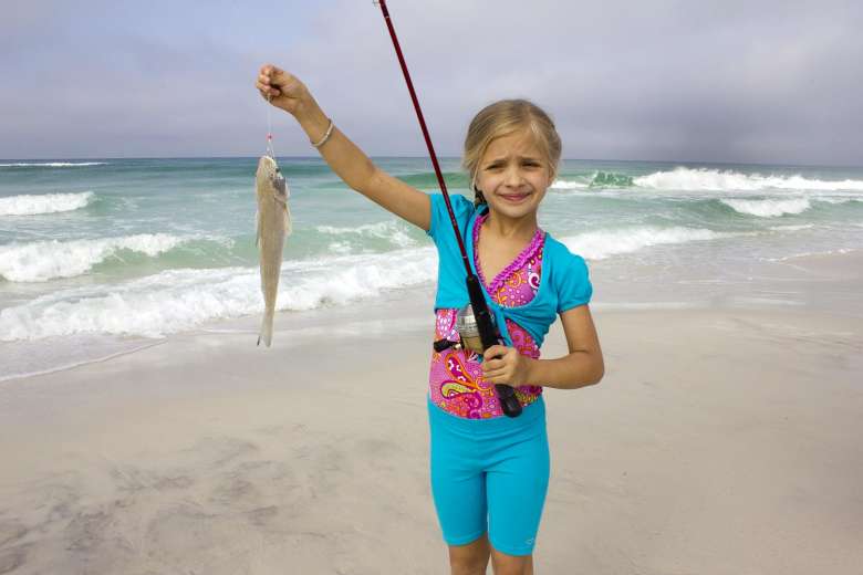 how to catch Gulf Kingfish - Young girl holding up a gulf kingfish, aka whiting, she caught from the beach