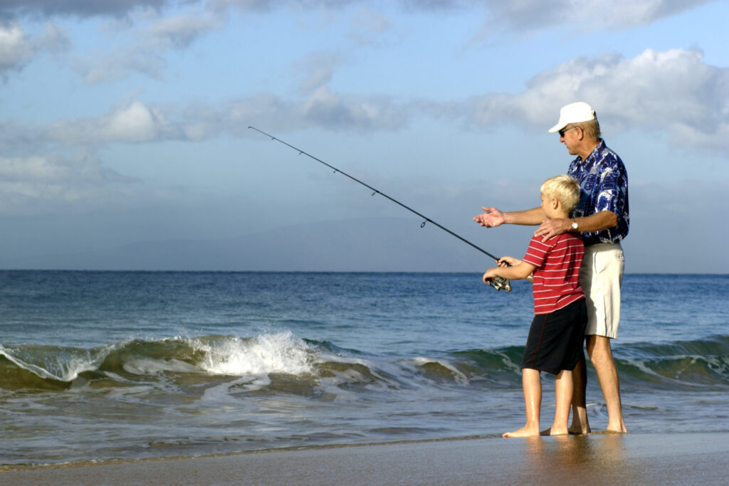 Father helping his son learn to surf fish