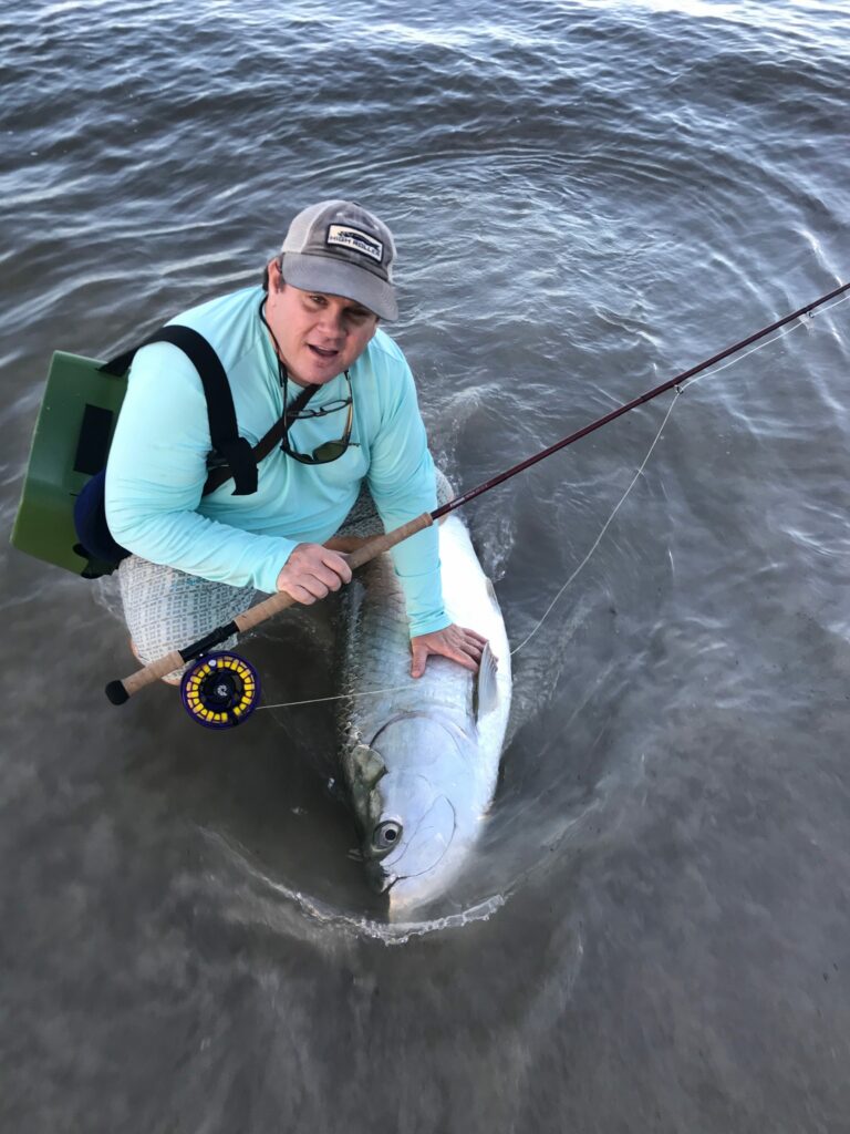 Fly angler with a large tarpon caught while fly fishing the surf