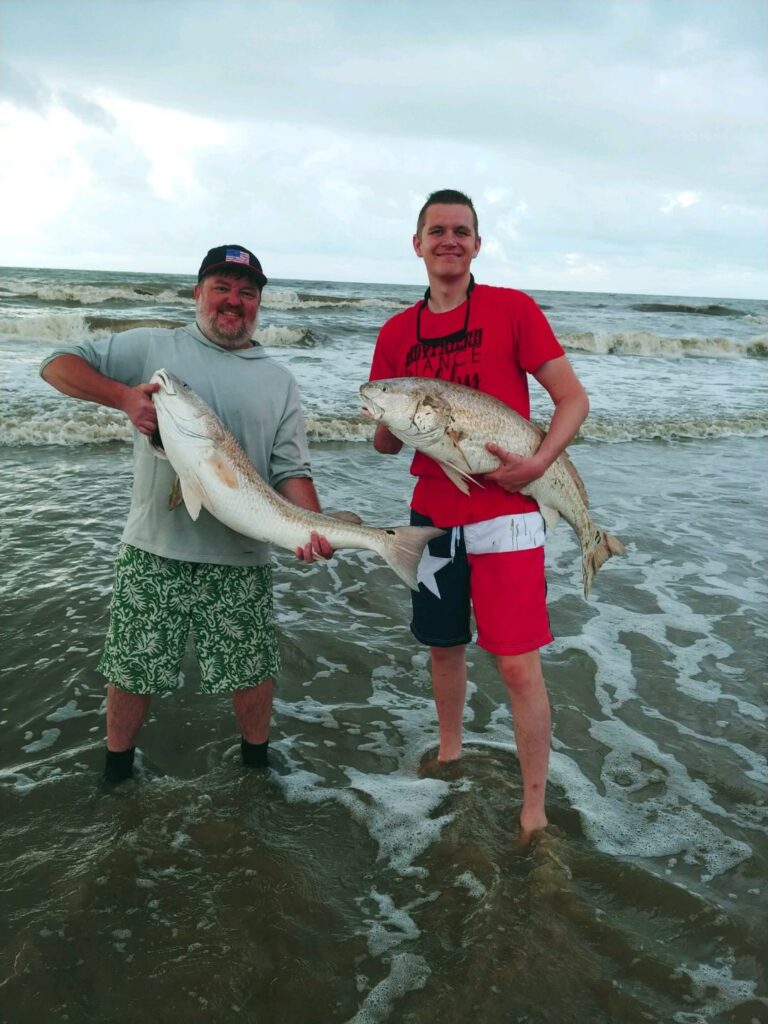 Surf Fishing Crystal Beach texas - Couple of anglers each holding up an oversized bull redfish caught from the Crystal Beach surf