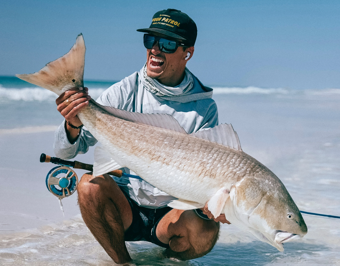 fly angler with a bull redfish caught while fly fishing the surf