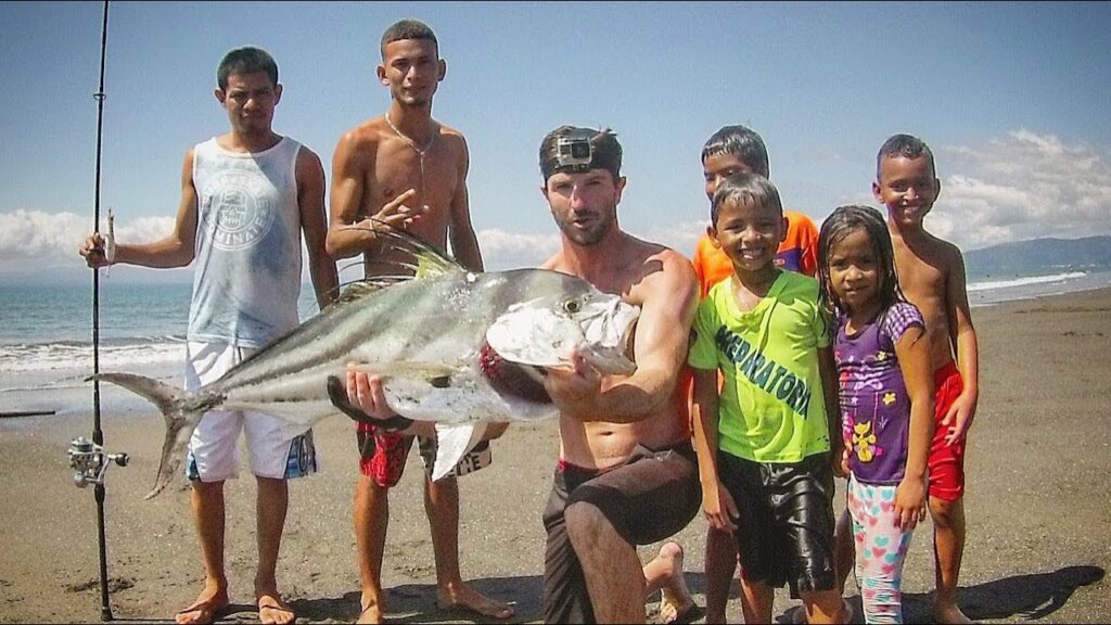 Beach fishing Costa Rica - Angler with a nice rooster fish caught from the beach in Costa Rica and surrounded by locals
