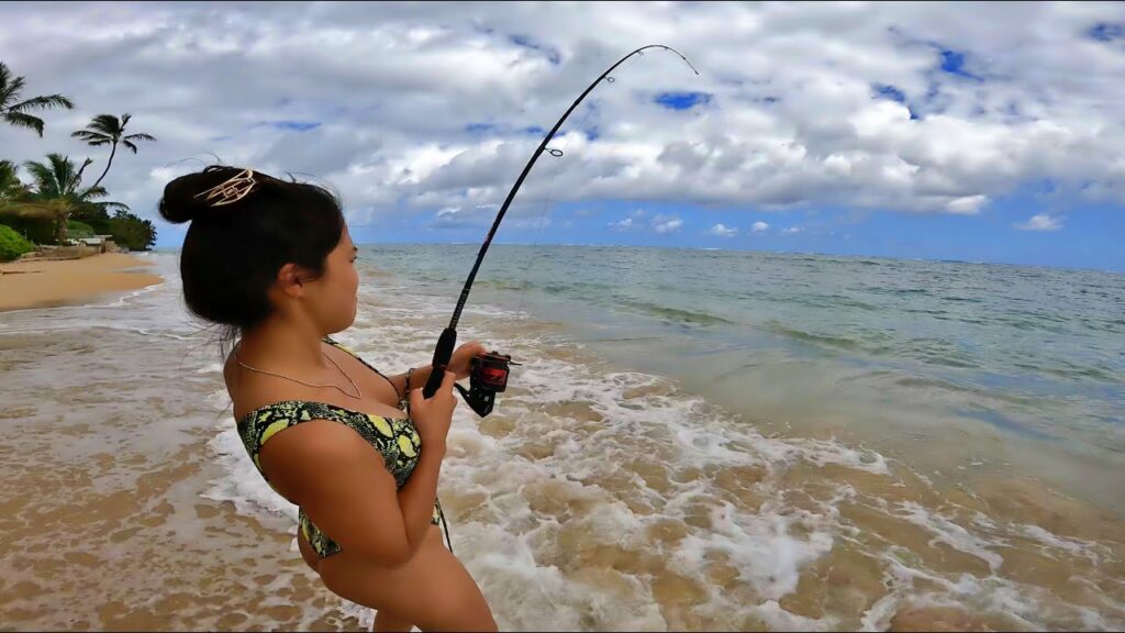 Lady angler hooked up with a big fish in the surf of Hawaii
