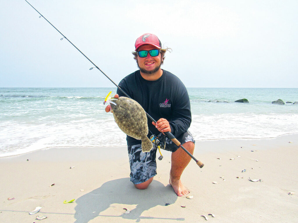 Angler kneeling on the beach with a nice flounder caught in the surf