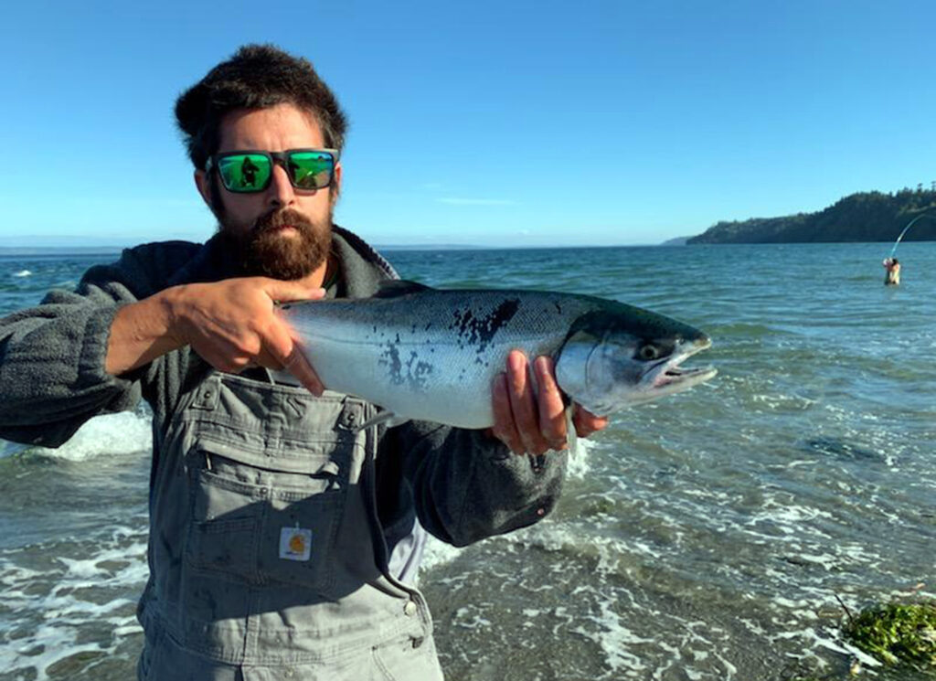 Angler holding a coho salmon caught while surf fishing the Washington Coast