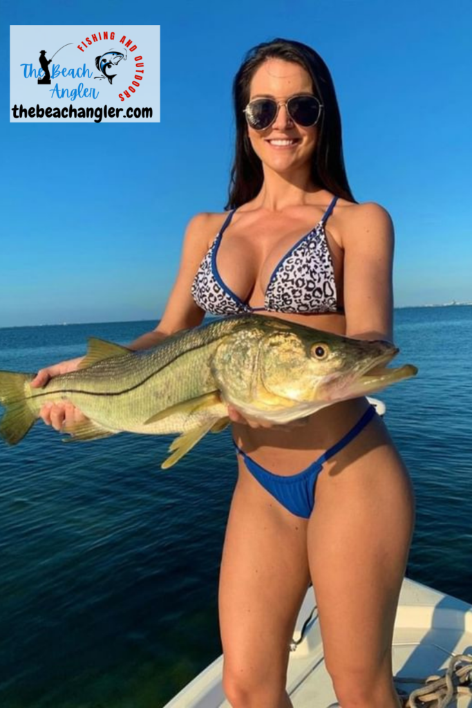 Surf Fishing for Snook - bikini clad lady angler standing in the bow of a boat holding a very large snook