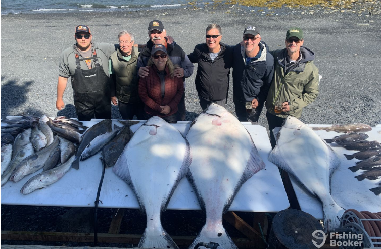 Successful catch with Discovery charters fishermen standing behind the cleaning tables loaded with halibut and salmon from a Kodiak Alaska Fishing adventure
