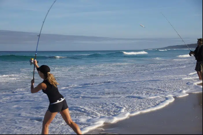 Lady angler surf casting from a beach in Australia