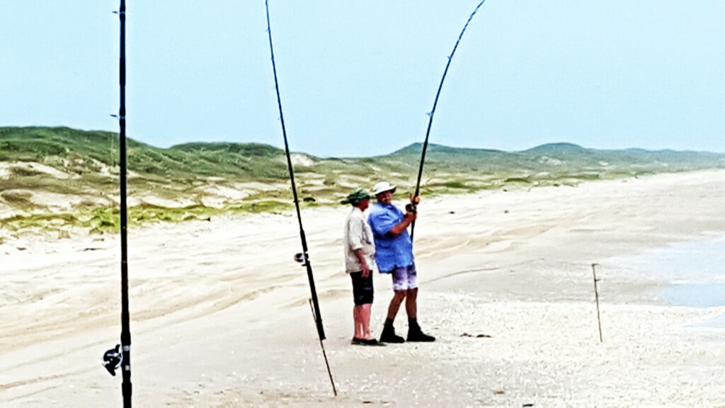 DIY surf fishing - Fishing Guide coaching an angler who is hooked up with a fish in the surf