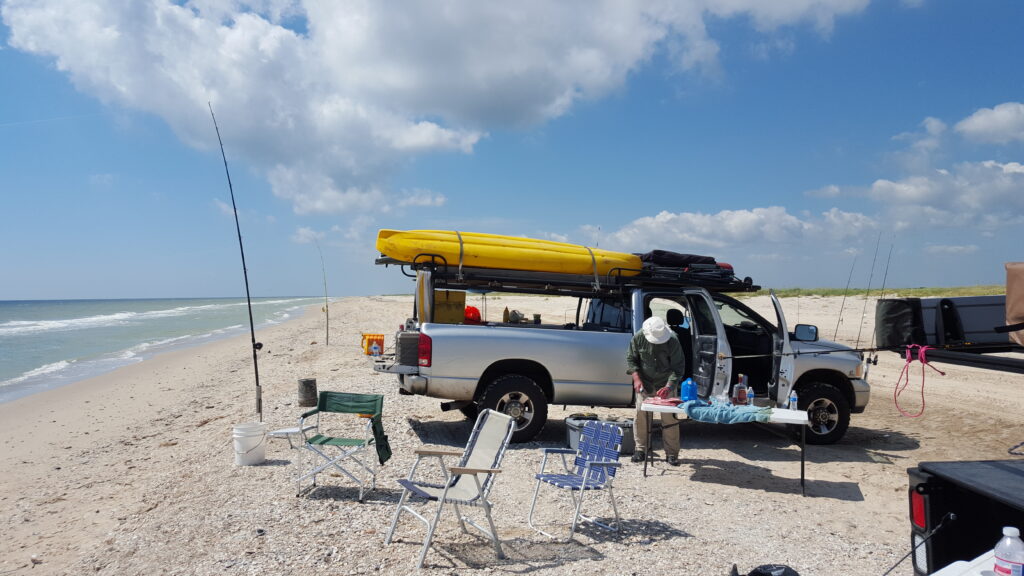 DIY Surf Fishing - Truck loaded with kayaks and rods set in sand spikes while surf fishing