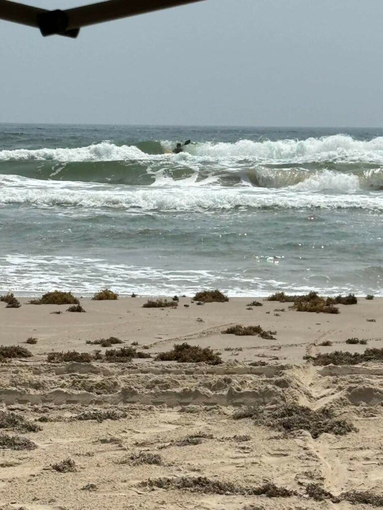 Kayaker taking shark baits off the beach in heavy surf conditions