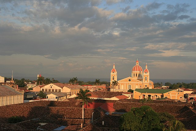 a photo of Granada Nicaragua at sunset with the light shining on the buildings highlighting the unique colonial architecture