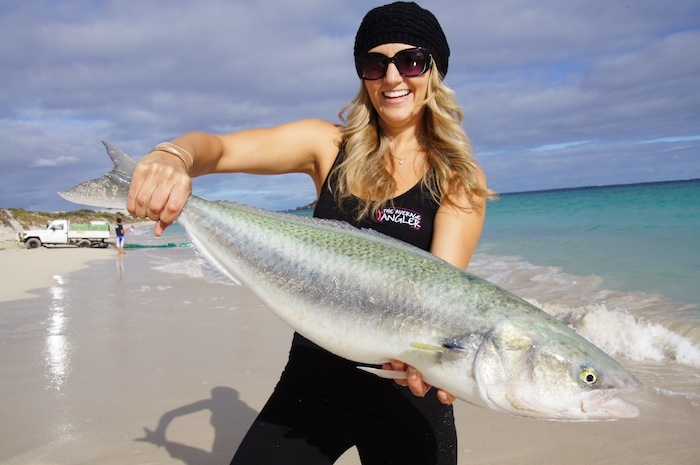Surf Fishing in Australia - A Lady angler kneeling on the beach with a large Australian Salmon caught while surf fishing.