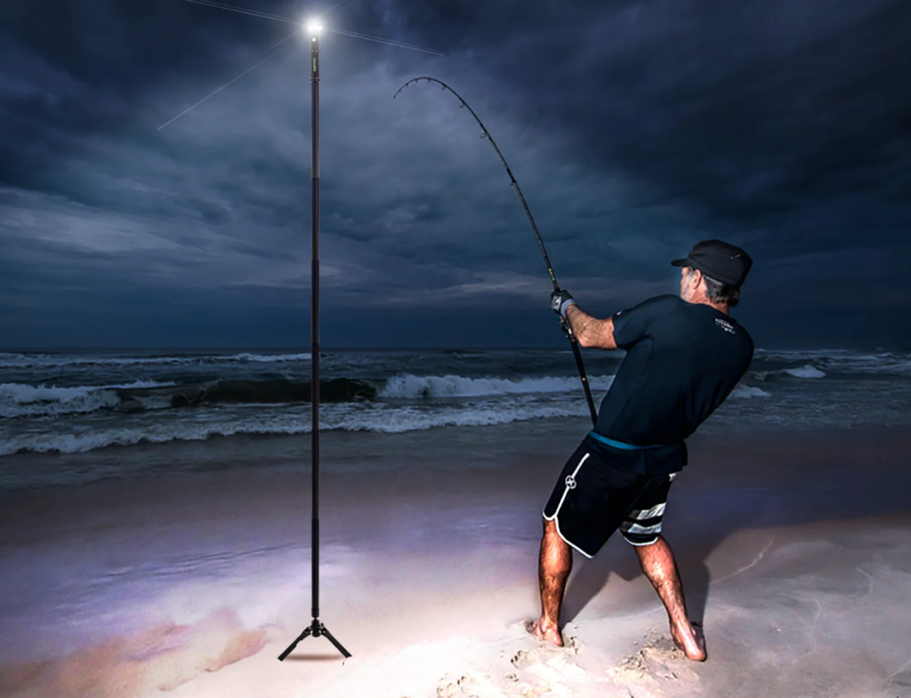surf fishing safety - surf angler hooked up while standing on the beach next to his LED tower light.