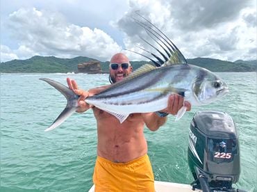 Roosterfish caught in Nicaragua with fisherman holding it up and the ocean and mountains in the background