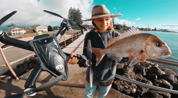 Beach angler holding a nice snapper caught using her Cuta Copter Trident Boss+ waterproof fishing drone