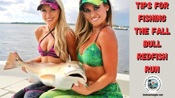 Two lady anglers holding a bull redfish in their laps while sitting in a boat