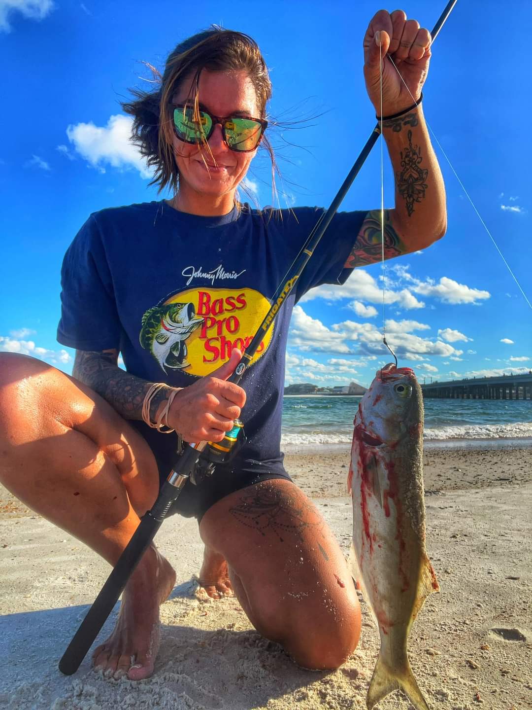 Catching Bluefish from the Beach - a Lady angler kneeling on the beach with a bluefish she has just caught from the beach