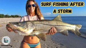 surf fishing after a storm showing a lady angler holding up a large Snook while standing on the beach