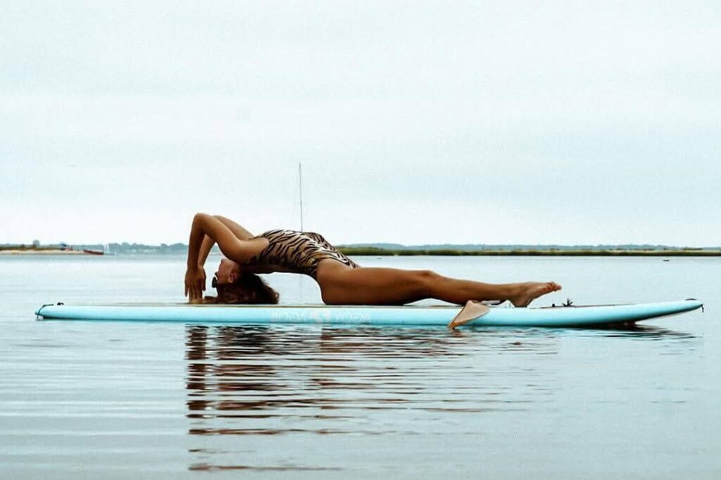 Lady practicing yoga moves on her stand up paddle board