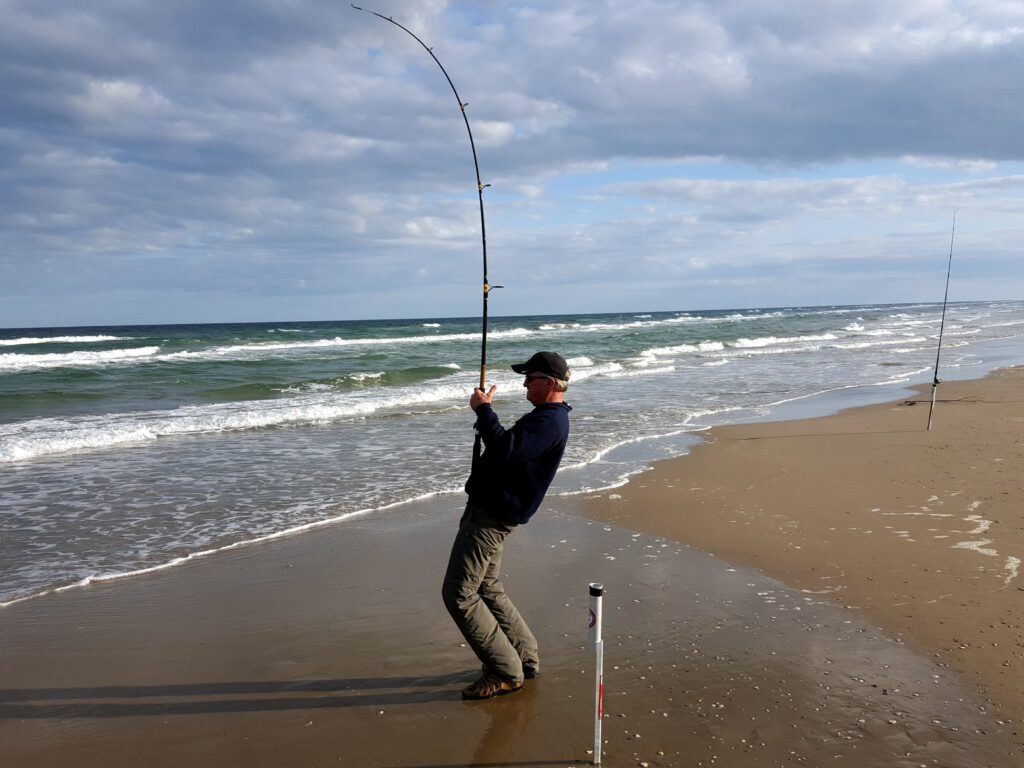 Gerald Gerwick fighting a fish in the surf of Padre Island National Seashore.